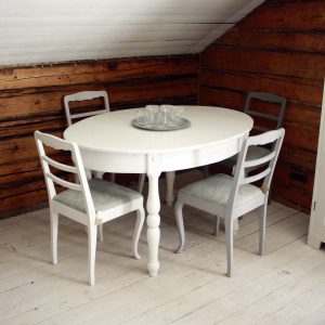 Ovaltbord med fyra stolar framför stockvägg